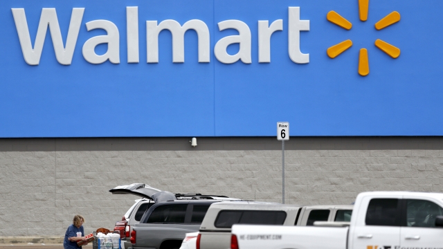 A woman pulls groceries from a cart to her vehicle outside of a Walmart store