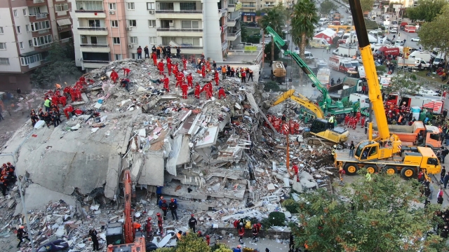 members of rescue services search for survivors in the debris of collapsed buildings in Izmir, Turkey.