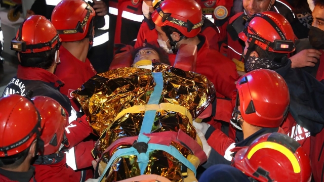 Rescue workers carry 14-year-old survivor from rubble.
