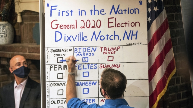 A man tallies the votes from the five ballots cast just after midnight, Tuesday, Nov. 3, 2020, in Dixville Notch, N.H.