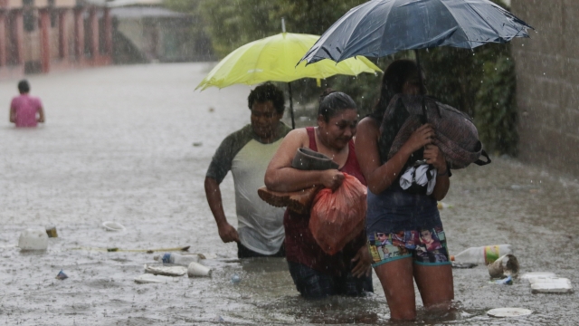 People wade through a flooded road carrying some belongings, in Progreso Yoro, Honduras, Wednesday, Nov. 4, 2020.