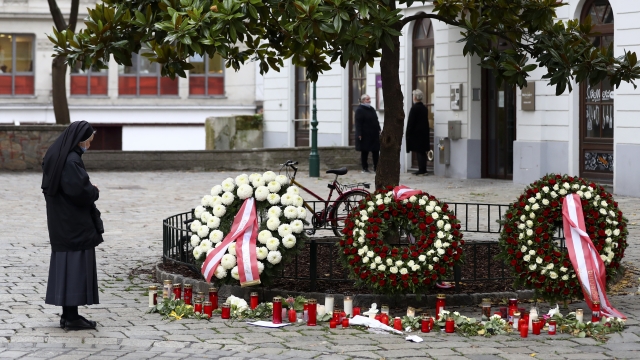 A nun stands at the crime scene besides wreaths and candles in Vienna, Austria.