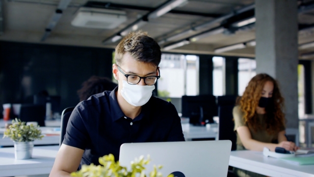 Man works in an office wearing a mask.