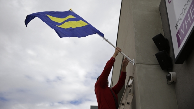 Logan Seven raises an equality flag on the front of the Chapelle de l'amore wedding chapel in Las Vegas.