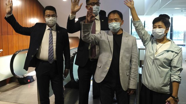 Pro-democracy legislators wave after handing their letters at Legislative Council in Hong Kong.