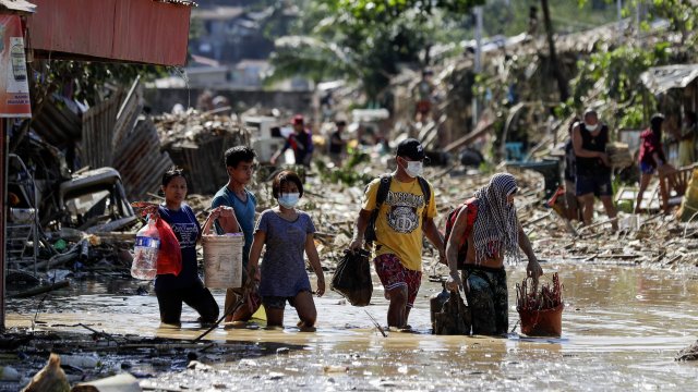 Phillipines residents walk through mud and debris