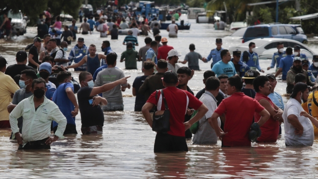 People wade through a flooded road in the aftermath of Hurricane Eta in Planeta, Honduras.