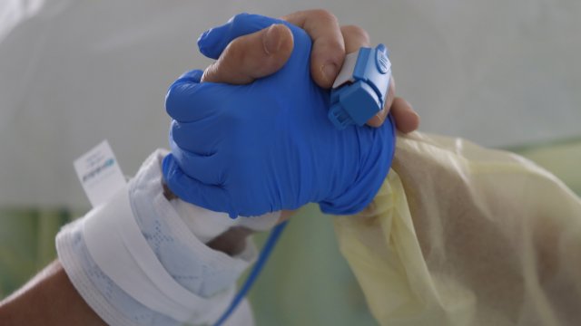 Therapist holds COVID patient's hand