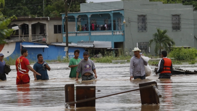 Men wade through a street flooded after the passing of Hurricane Iota in La Lima, Honduras, Wednesday, Nov. 18, 2020.