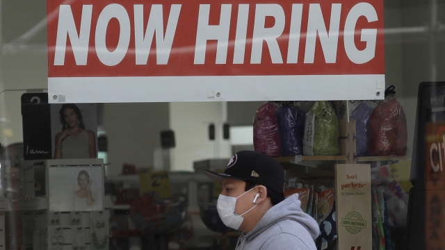A man wearing a mask while walking under a Now Hiring sign at a CVS Pharmacy in San Francisco in May 2020.