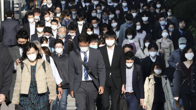 Commuters wearing face masks to protect against the spread of the coronavirus walk on a street in Tokyo, Japan