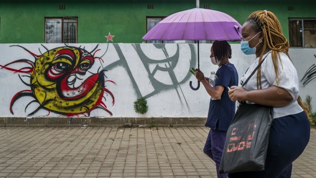 Two women walk past a COVID-19 graffiti
