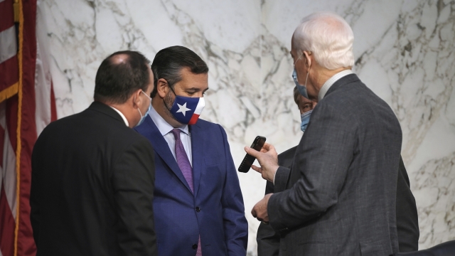 Sens. Mike Lee and Ted Cruz, R-Texas, look at the phone of Sen. John Cornyn