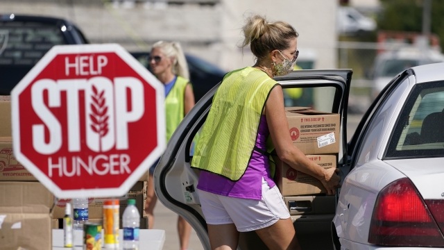 A volunteer loads a local resident's vehicle at a drive-up produce giveaway organized by a Des Moines, Iowa, food pantry
