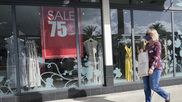 A shopper walks by a store advertising a sale.