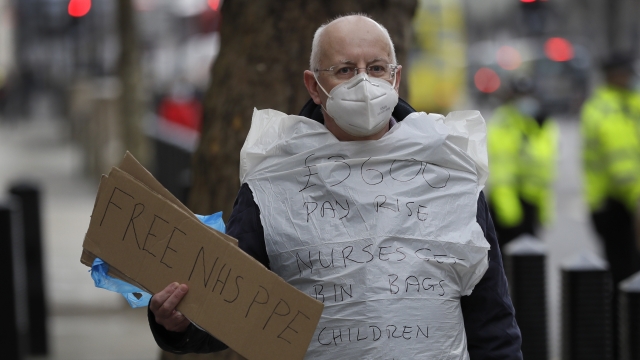 A man campaigning for NHS PPE stands outside parliament in London