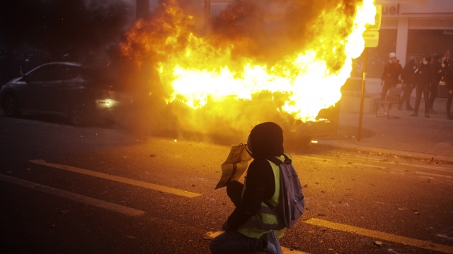 Protester kneels in front of a burning car in Paris