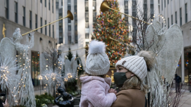 A woman holds her daughter as they look at the Rockefeller Center Christmas Tree
