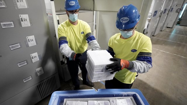 Masked workers prepare coolers of the COVID-19 vaccine to be shipped from Michigan.