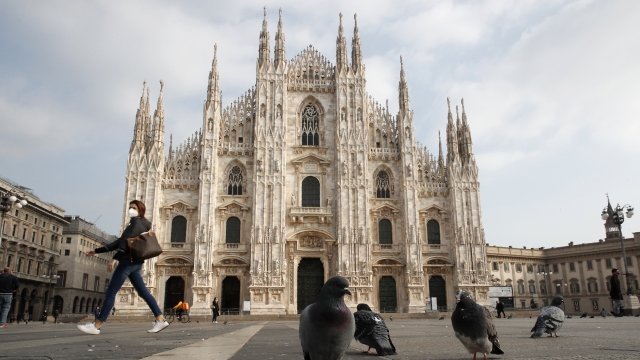 A woman walks past the gothic cathedral in Milan, Italy that is part of the red zone.