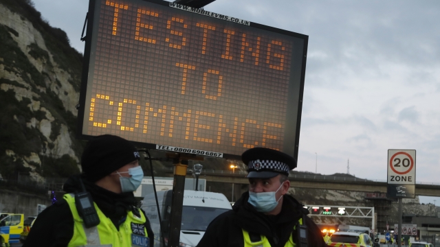 Police next to sign about coronavirus testing.