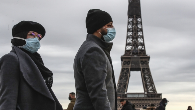 A man walks in front of the Eiffel Tower in Paris, France wearing a face mask