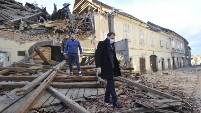 People move through remains of a building damaged in an earthquake, in Petrinja, Croatia
