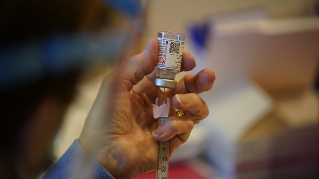 fills a syringe with Moderna COVID-19 vaccine
