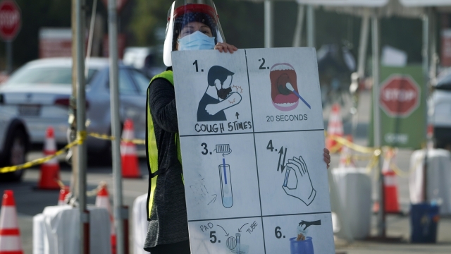 A worker holds sign for drive-thru COVID testing