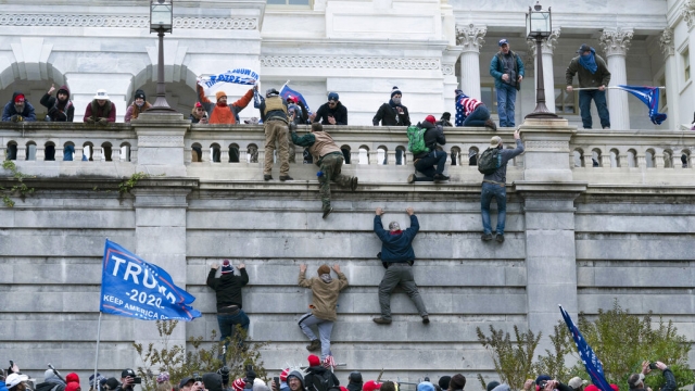 Rioters scale a wall at the U.S. Capitol building