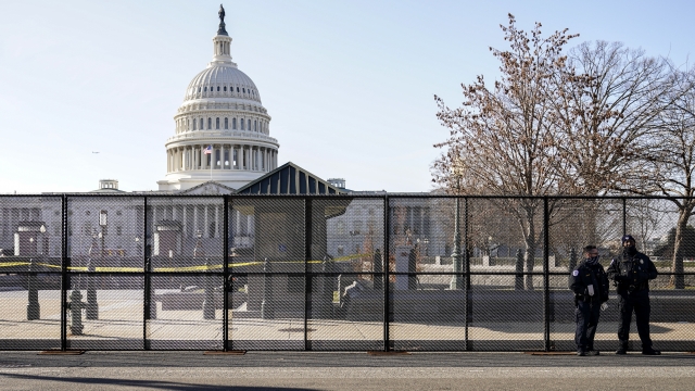 Capitol police officers stand outside of fencing that was installed around the exterior of the Capitol grounds