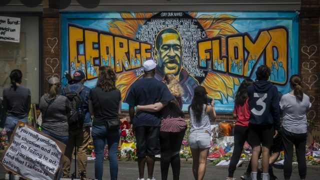 Visitors mourn the death of George Floyd in front of a mural.