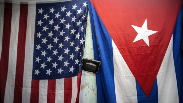 A U.S. and Cuban flags hang from a wall with an old photo camera hung in between in Havana, Cuba