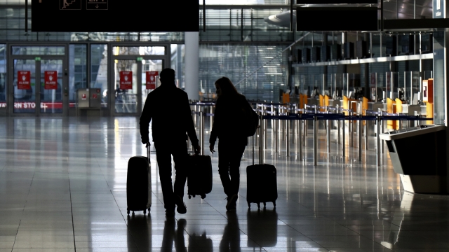 People walk with their luggage through a deserted check-in hall at the airport in Munich, Germany