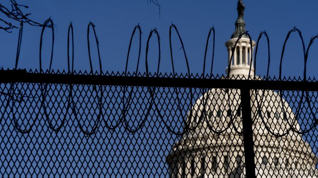 The Dome of the Capitol Building is visible through razor wire installed on top of a fence