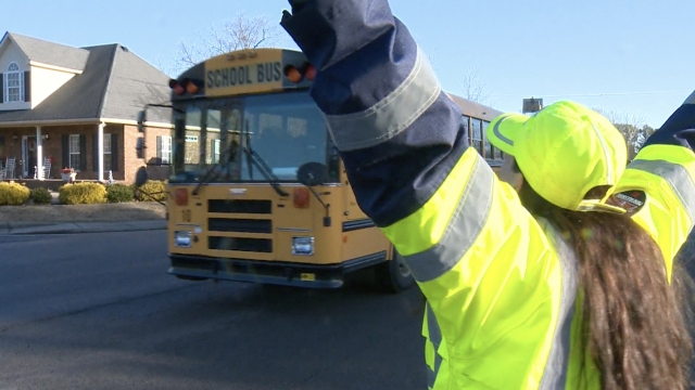 Crossing guard welcomes a bus.