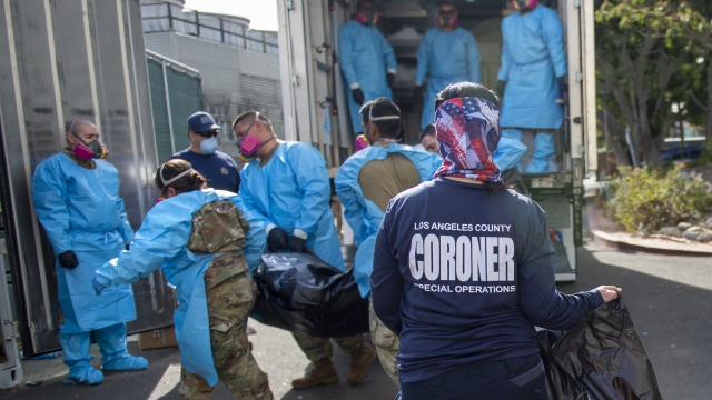 Coroner Elizabeth "Liz" Napoles, right, works alongside with National Guardsmen who are helping to process COVID-19 deaths