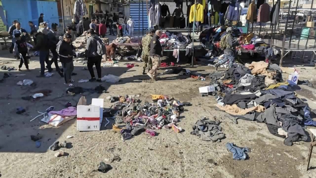 People and security forces gather at the site of a deadly bomb attack in an Iraqi market selling used clothes