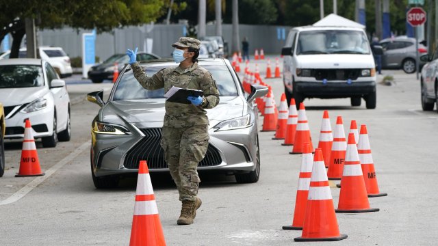 A member of the Florida National Guard directs vehicles at a drive-thru COVID-19 vaccination site at Marlins Park.