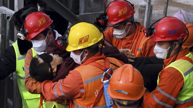 Rescuers carry a miner who was trapped in a mine to an ambulance.