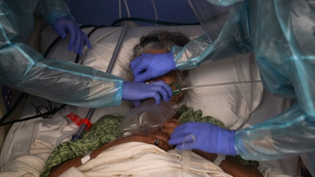A patient has a ventilator placed on her by two nurses