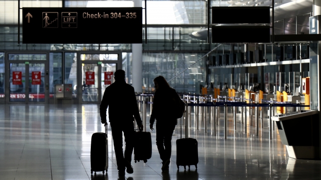 Travelers walk through a deserted check-in hall at the airport in Munich, Germany