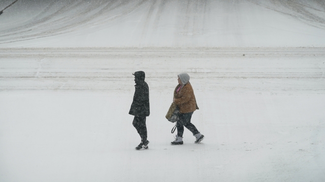 Pedestrians cross a snow covered street
