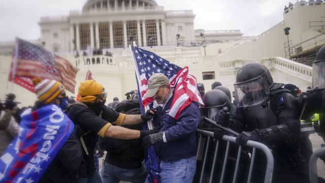 rioters try to break through a police barrier at the Capitol in Washington