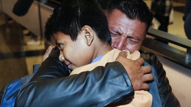 A Guatemalan migrant hugs his son as they reunite after being separated