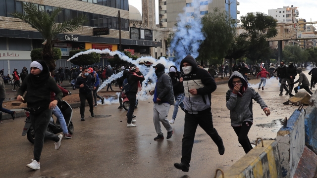 Protesters run from tear gas canisters during a protest.