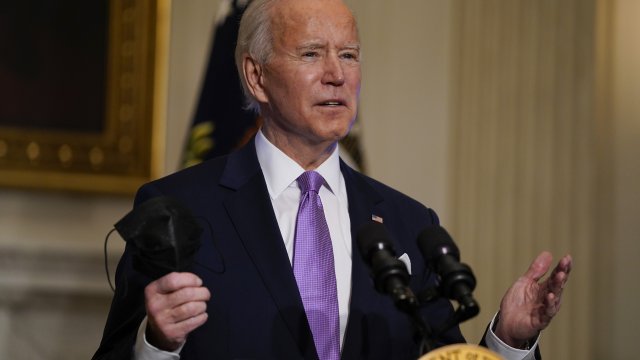 President Joe Biden holds his face mask as he delivers remarks on COVID-19