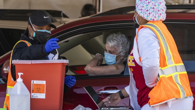a woman is vaccinated inside her vehicle at a mass COVID-19 vaccination site in California.