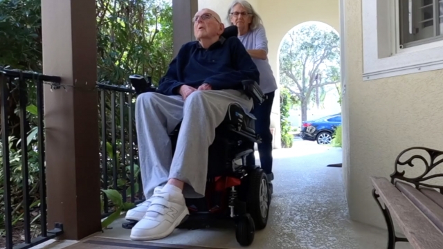 Wife pushes husband in his wheelchair
