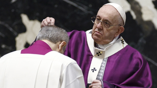 Pope Francis sprinkles a clergyman with ashes